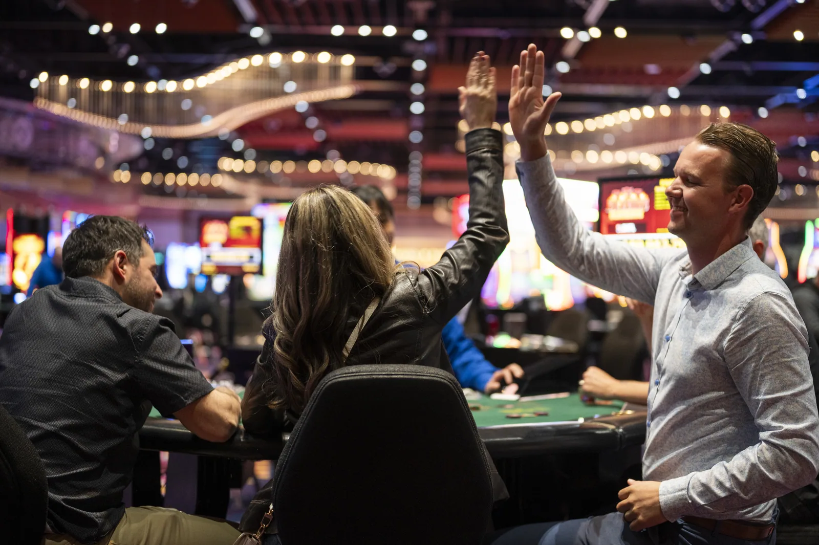 Man and woman high-fiving at a card table in a casino