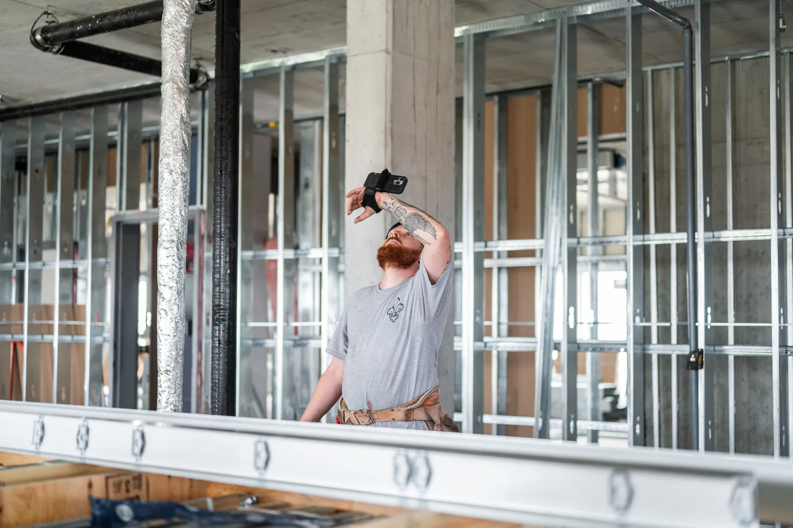 Construction worker with phone-mounted device inspecting unfinished building interior