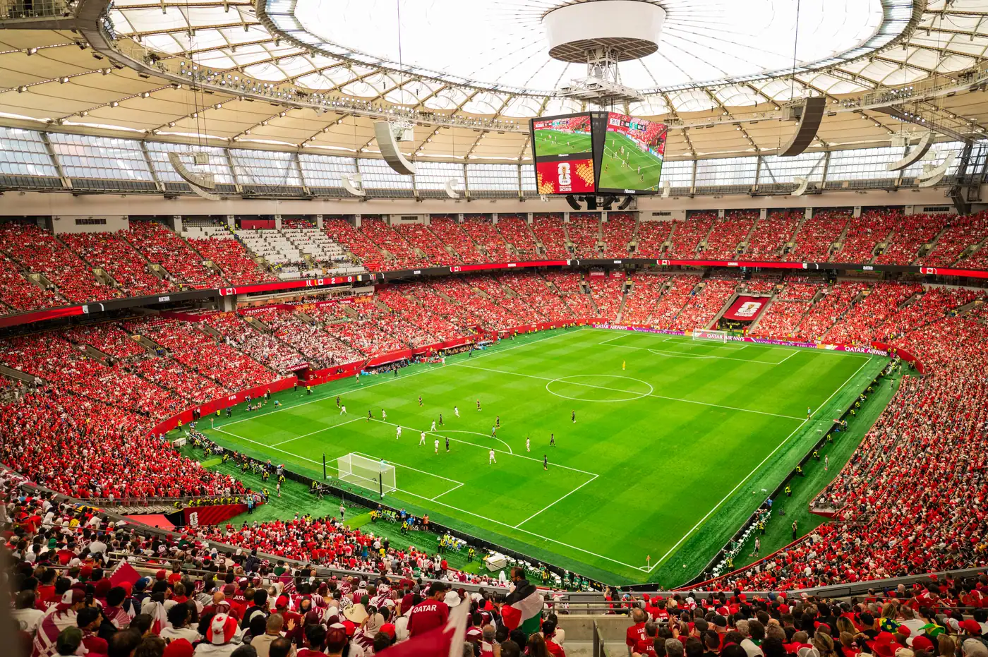 World Cup soccer stadium filled with cheering fans, large video screen, and green field