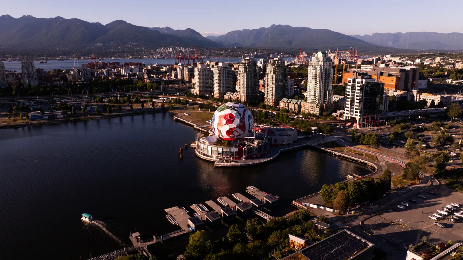 Vancouver cityscape from above, featuring False Creek, mountains, and a large soccer ball structure